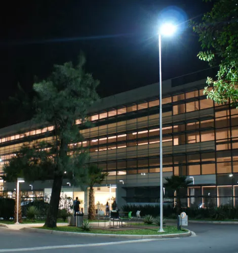 Prédio corporativo do E-Business Park à noite, com iluminação interna e externa acesa