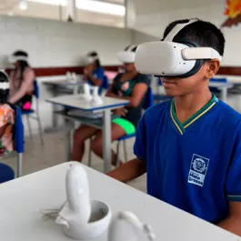 estudante em sala de aula com uniforme azul e óculos de realidade virtual