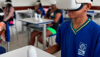 estudante em sala de aula com uniforme azul e óculos de realidade virtual